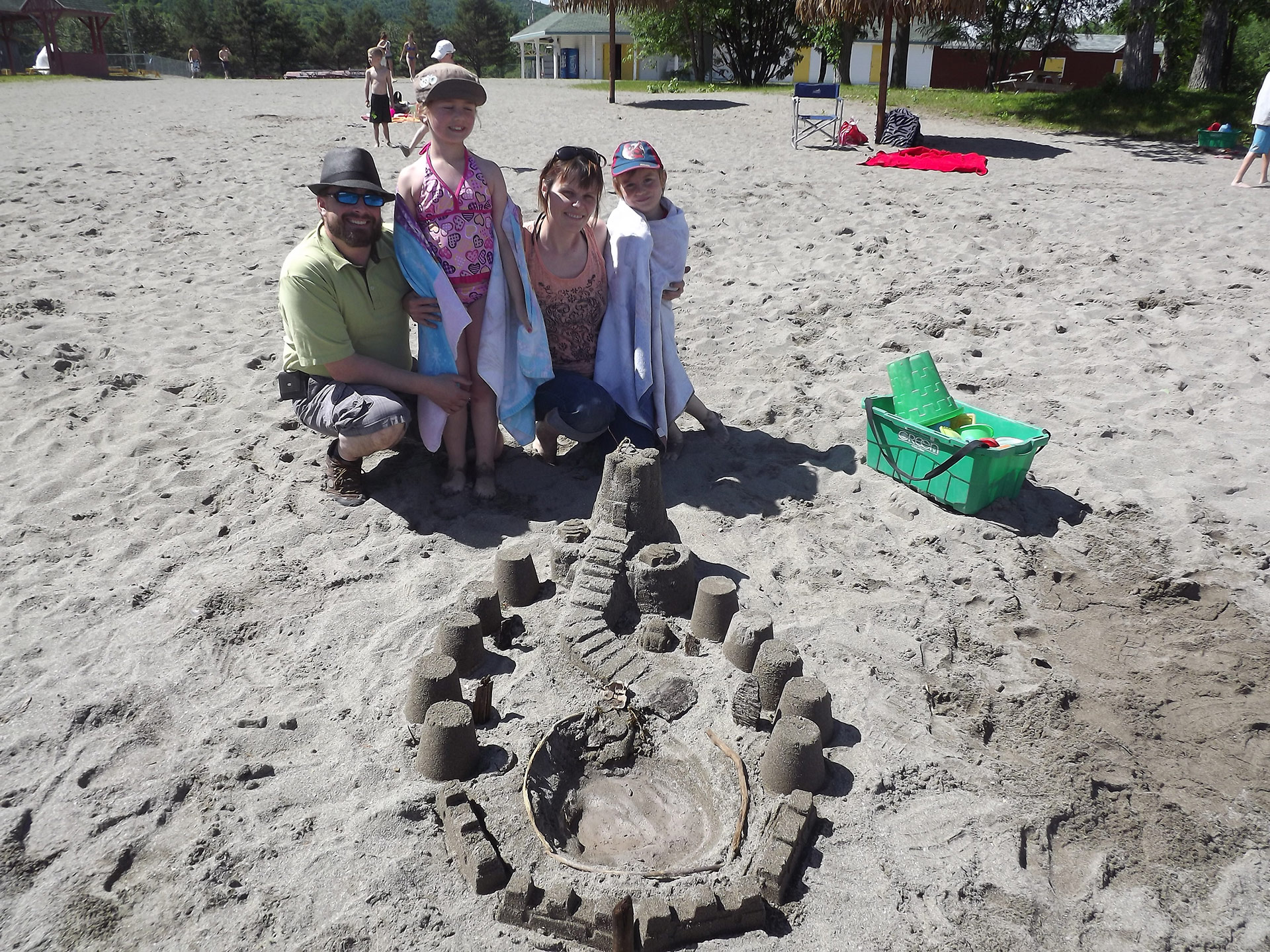 Une famille fait un chateau de sable sur la plage du lac Pohénégamook